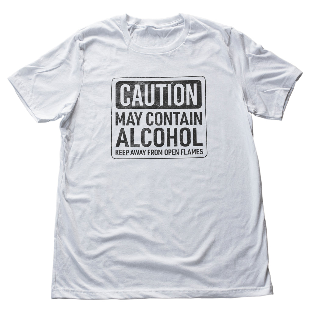 A graphic t-shirt with a sarcastic, parody theme, imitating a classic "caution" sign, but here it reads "Caution, May contain alcohol — keep away from open flames" as if to humorously suggest the wearer has been drinking.  