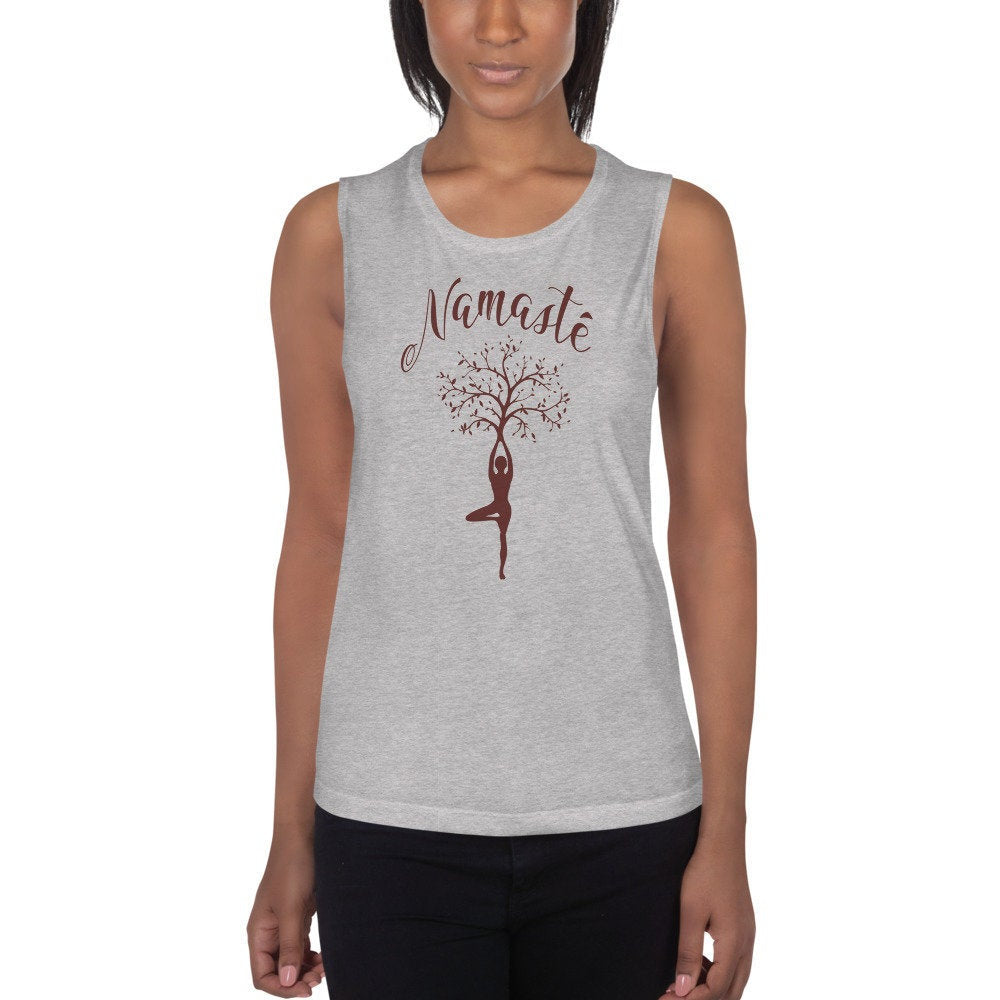 Female model wearing an elegant, fashionable graphic tank t-shirt featuring the calligraphy-inspired word "Namasté" above the illustration of a woman in a yoga pose, with a tree sprouting from her raised hands.