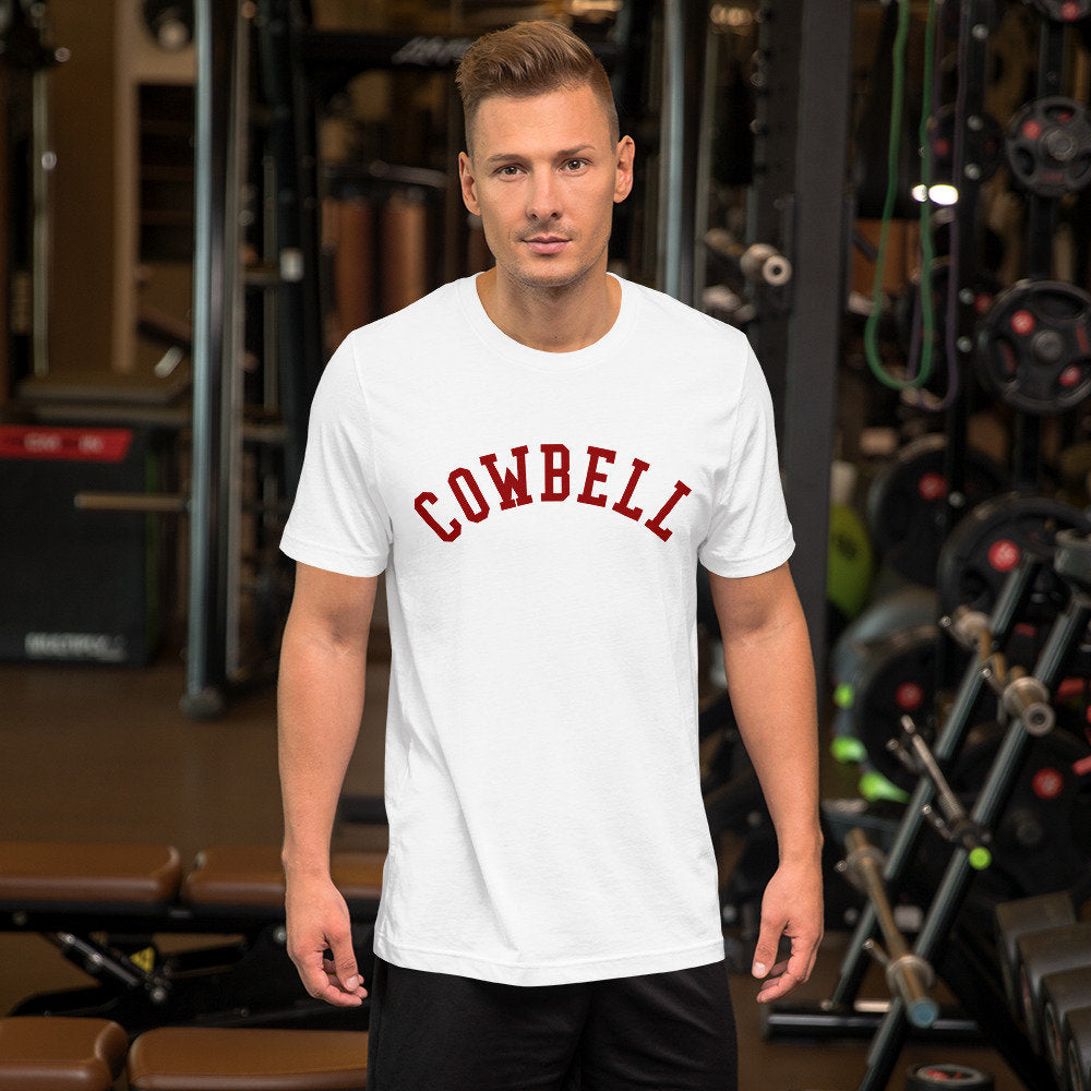 Fashionable graphic t-shirt with the word "COWBELL" in an arch, referencing the Saturday Night Live skit of a Blue Oyster Cult recording session, but in a typographic treatment like a College (Cornell) jersey.