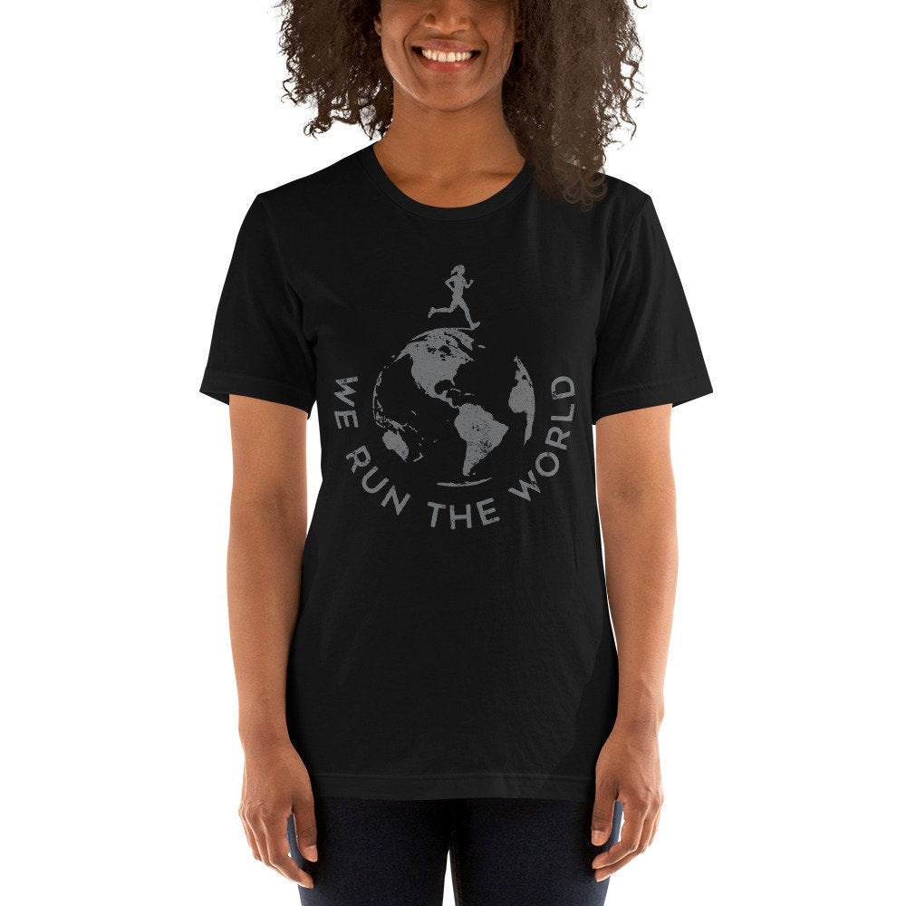 Female model wearing a graphic t-shirt for runners and joggers, with an illustration of the globe, and text encircling it that reads "We Run the World" as a double-entendre about running and dominating.