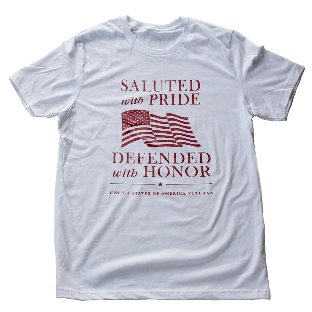 Classic design graphic t-shirt honoring american Veterans and Military personnel, with the phrase "Saluted with pride — defended with honor" around a waving American flag.