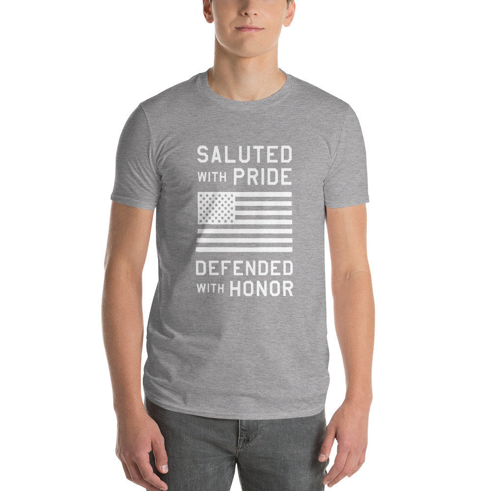 Classic, retro design graphic t-shirt, honoring American veterans and military. It reads: "Saluted with Pride / Defended with Honor" around an iconic American flag.
