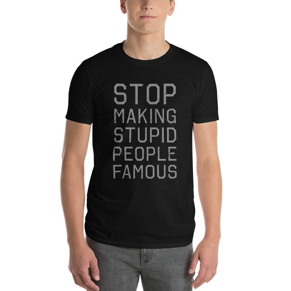 A classic, retro design graphic t-shirt featuring bold typography that reads "Stop making stupid people famous" — a play on a common meme with an indictment of social media.